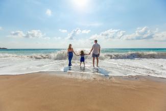 man, woman and child holding hands on seashore by Natalya Zaritskaya courtesy of Unsplash.