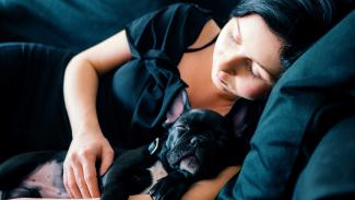 woman and black French bulldog sleeping on sofa by Rafal Jedrzejek courtesy of Unsplash.